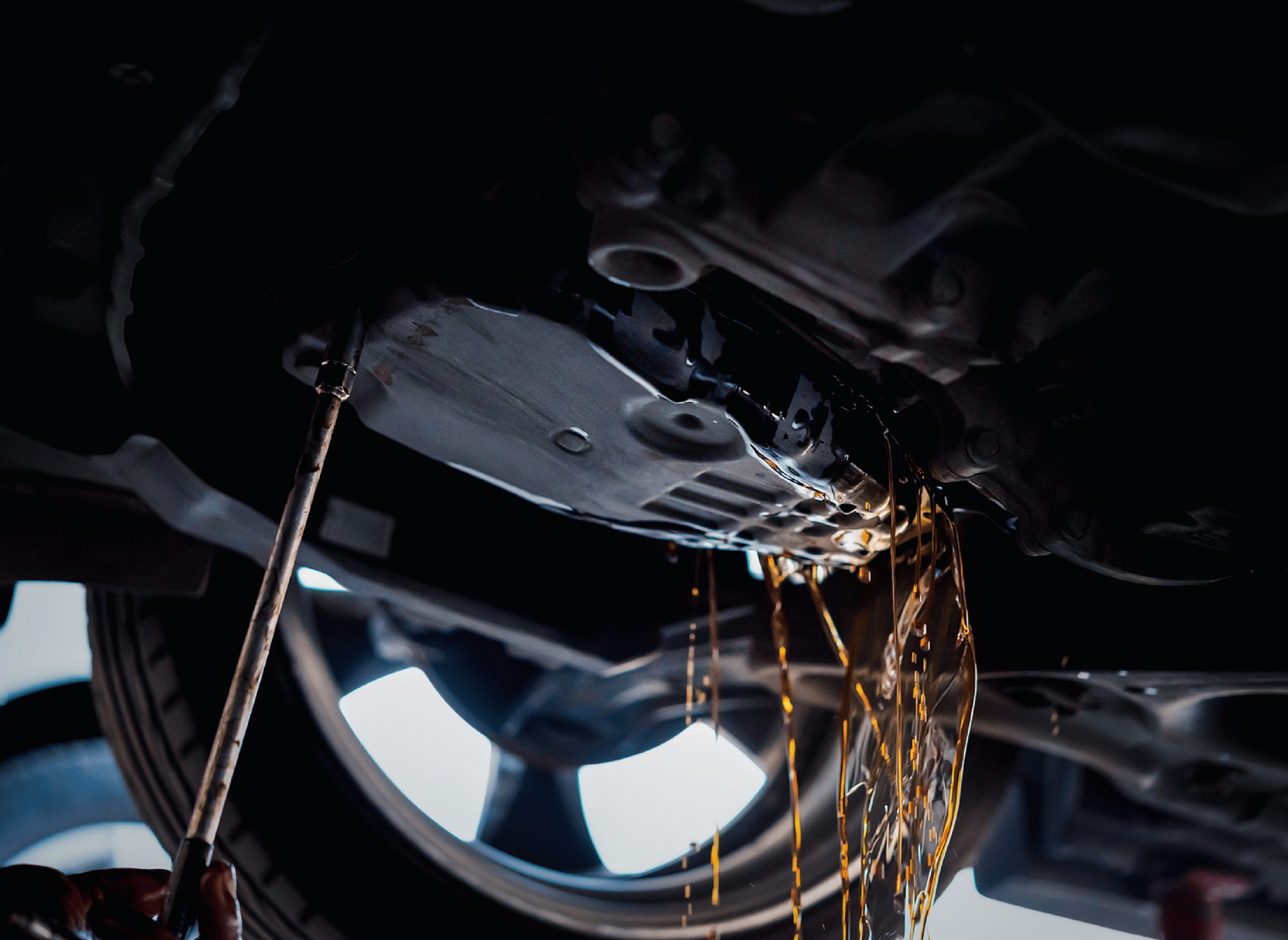 Image of an auto mechanic's hand and tool while changing transmission fluid at the underside of a vehicle. Concept image of filter replacement and fluid changes at Independent Auto and Diesel Repair.
