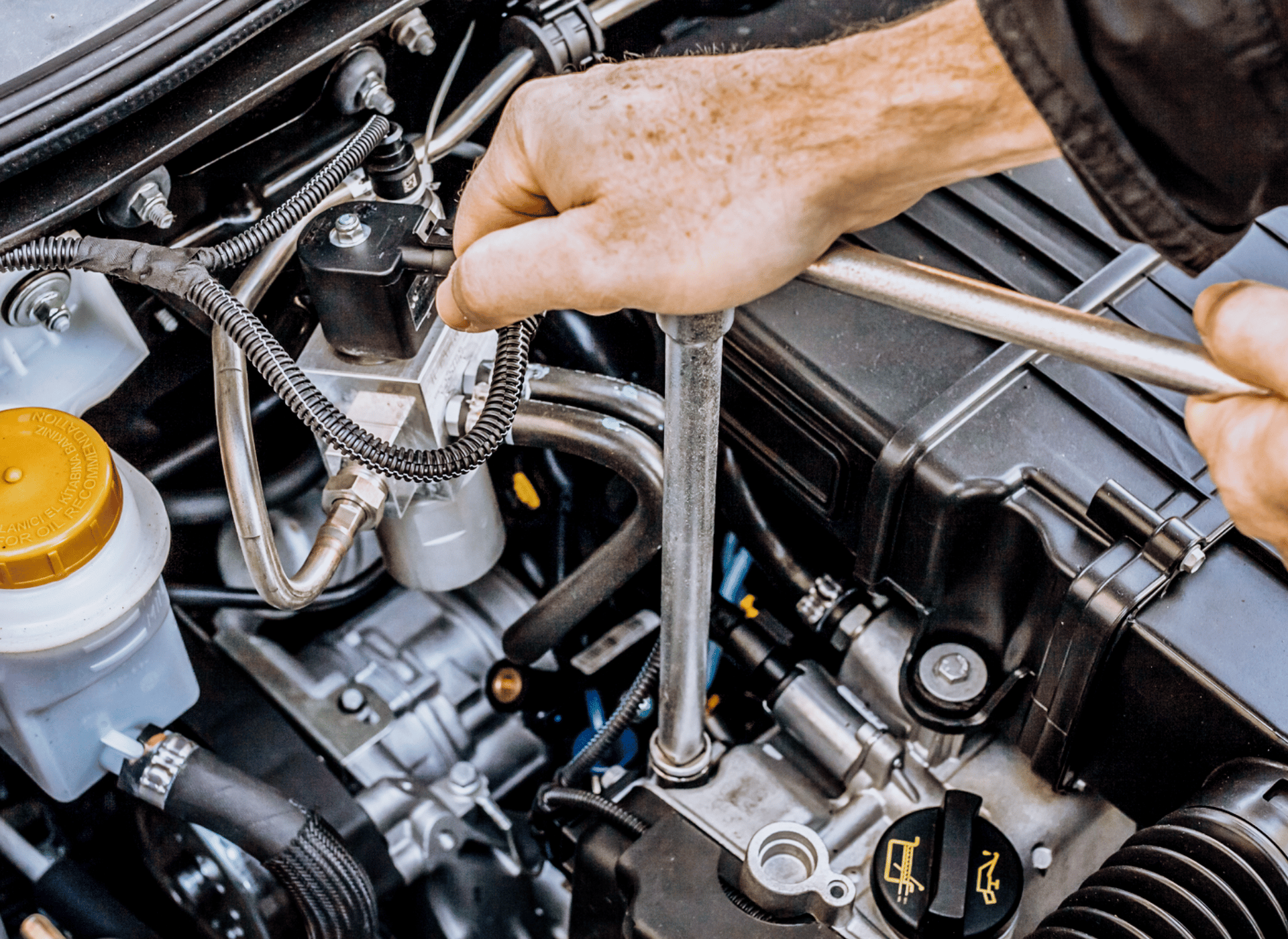 Image of an auto mechanic's ahnd holding a tool and working on an engine. Concept image of auto repair and maintenance at Independent Auto and Diesel Repair.