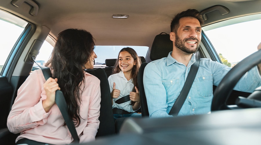 Holiday Vehicle Maintenance Tips | Independent Auto & Diesel Repair Jamestown. Image of happy mom, dad and daughter driving in car.