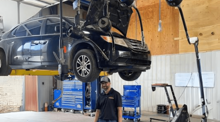 Best auto repair shop near me in Jamestown, TN with Independent Auto and Diesel Repair. Image of happy mechanic walking underneath a black ford suv on car lift in shop for auto repair services and maintenance.