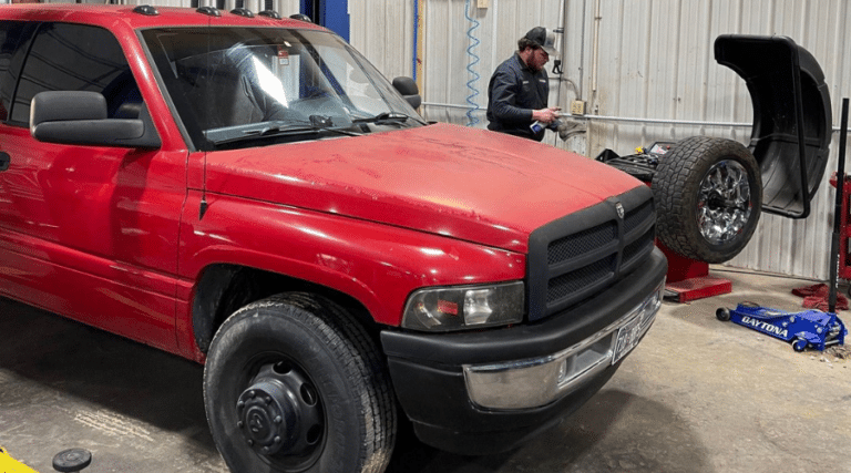 Spring maintenance service near me in Jamestown, TN with Independent Auto and Diesel Repair. Image of a red car at the auto shop with the mechanic getting ready to perform vehicle maintenance.