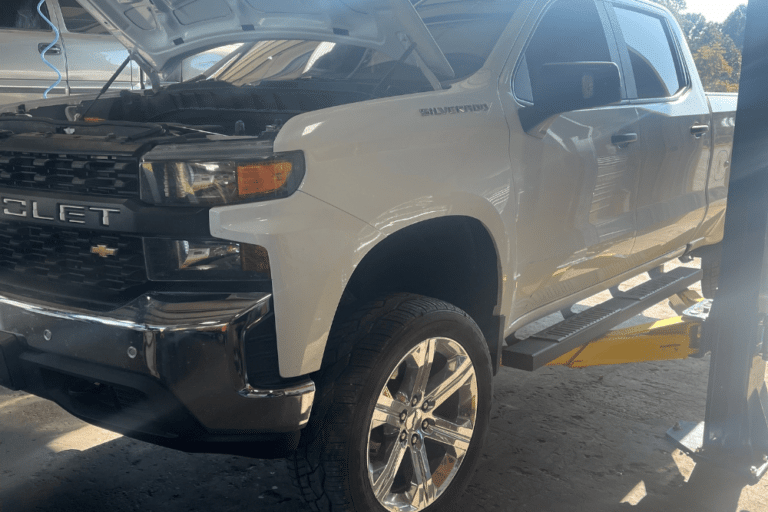 diesel engine maintenance, auto and diesel repair in Jamestown, TN at Independent Auto and Diesel Repair. Image of a white Chevrolet Silverado on a lift with the hood open, undergoing professional maintenance.