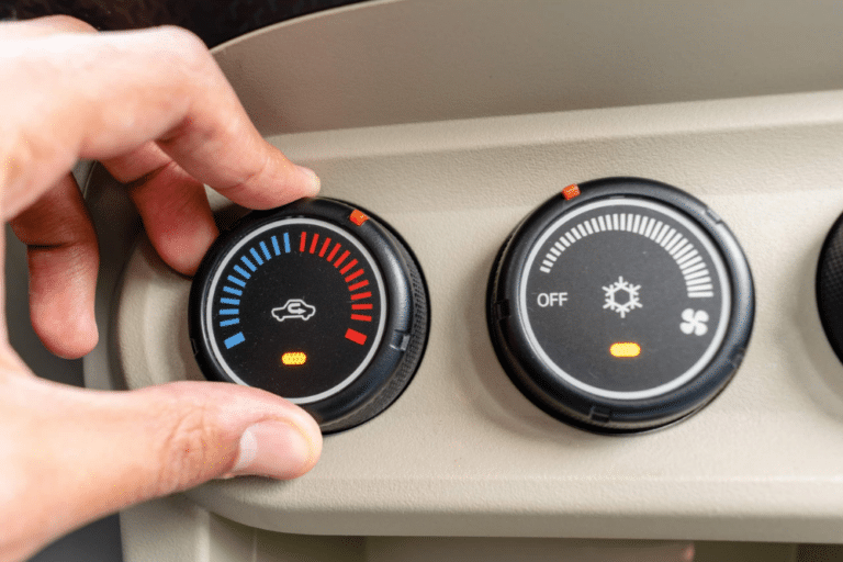 Auto A/C Service in Jamestown, TN At Independent Auto and Diesel Repair. A hand turning a car's dashboard temperature control dial toward the cold blue setting.